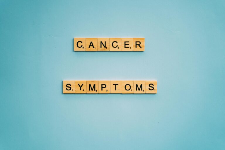 Scrabble tiles spelling 'Cancer Symptoms' on a light blue background, symbolizing awareness.