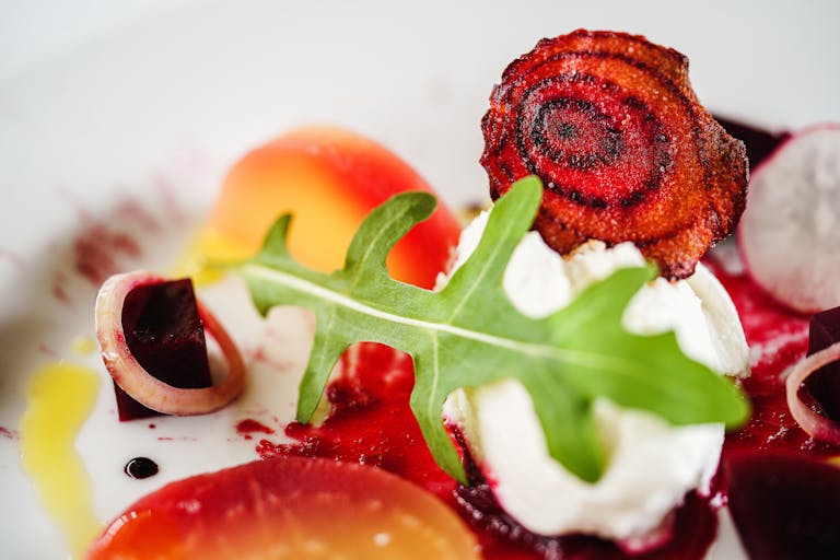Close-up of a vibrant salad featuring goat cheese, roasted beets, arugula, and onion rings.