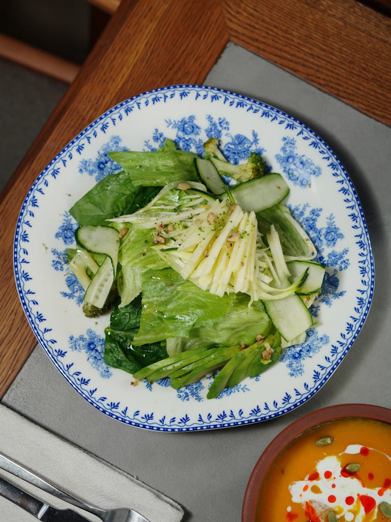 Crisp green salad served in a blue patterned bowl on a wooden table.