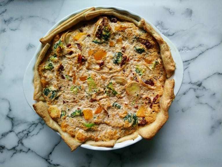 Delicious vegan quiche featuring broccoli, onions, and herbs in a flaky crust, perfect for brunch.