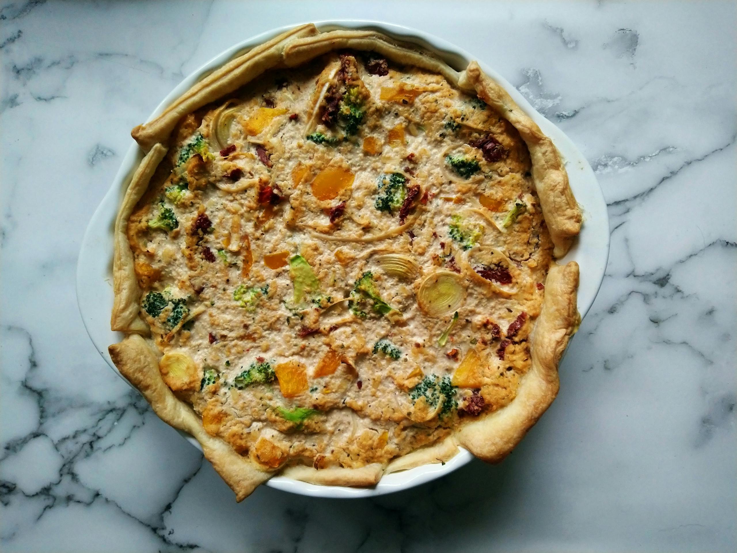 Delicious vegan quiche featuring broccoli, onions, and herbs in a flaky crust, perfect for brunch.