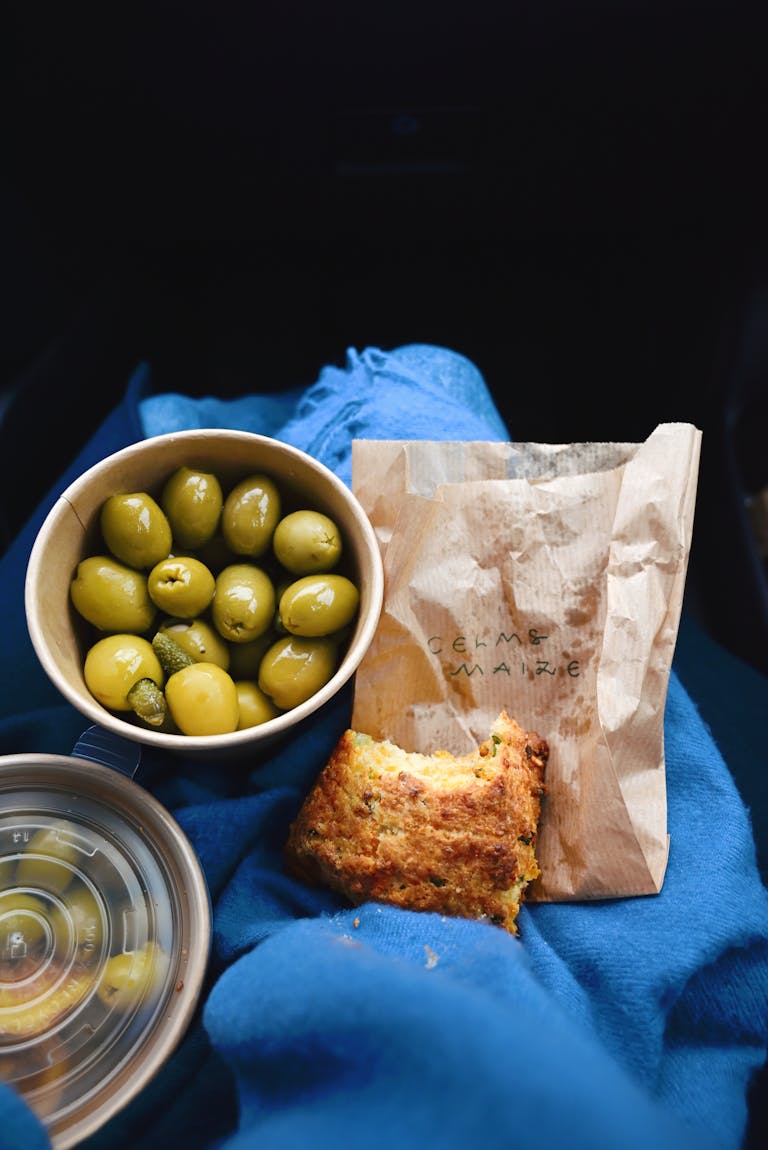 Green olives and cornbread on a blue blanket, perfect for a cozy snack.