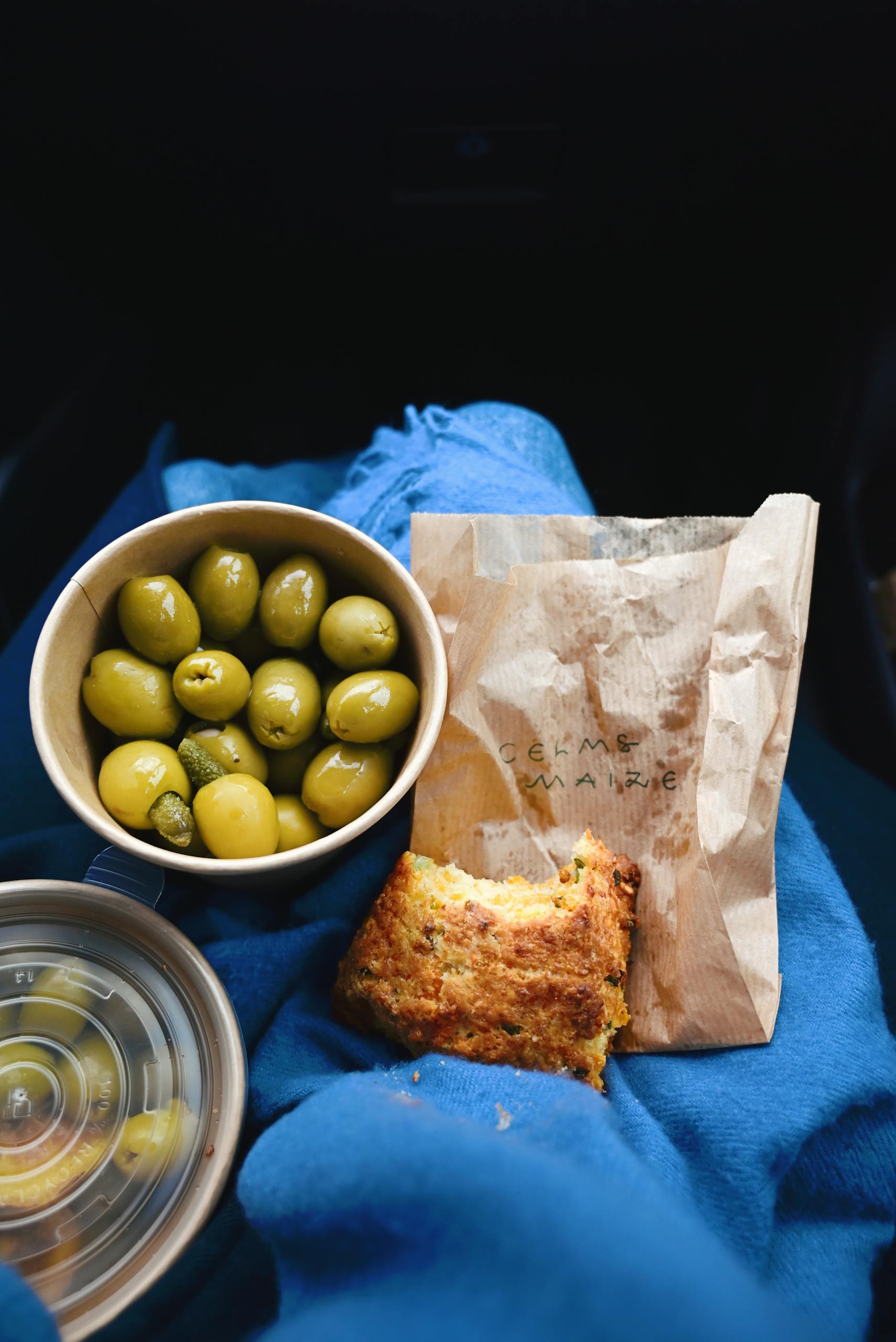 Green olives and cornbread on a blue blanket, perfect for a cozy snack.
