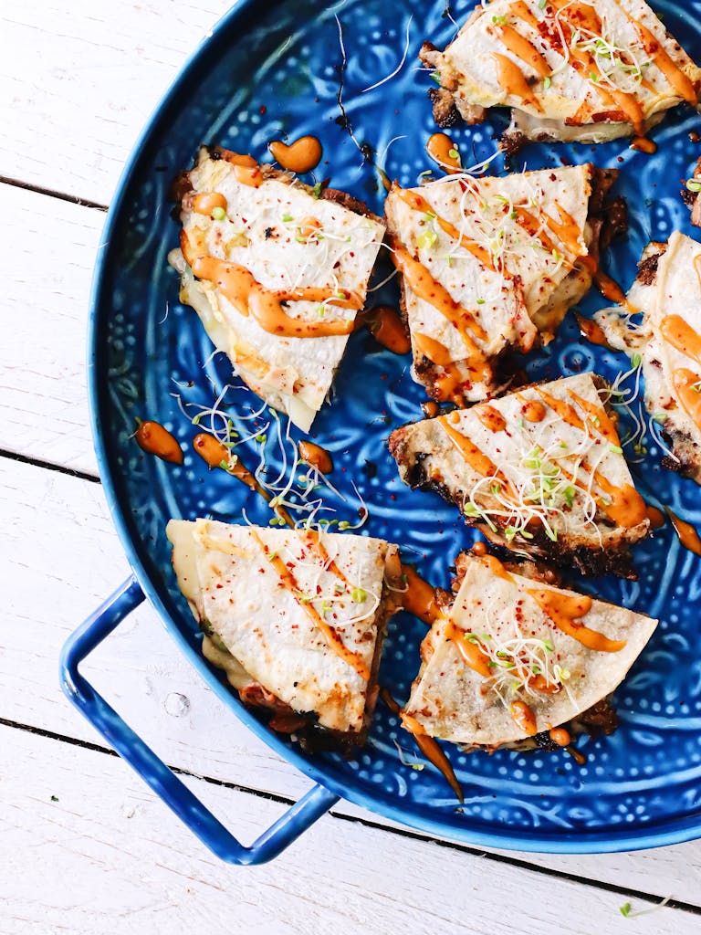 Overhead delicious triangle tortillas with vegetables topped with fresh sauce and served on blue ornamental plate